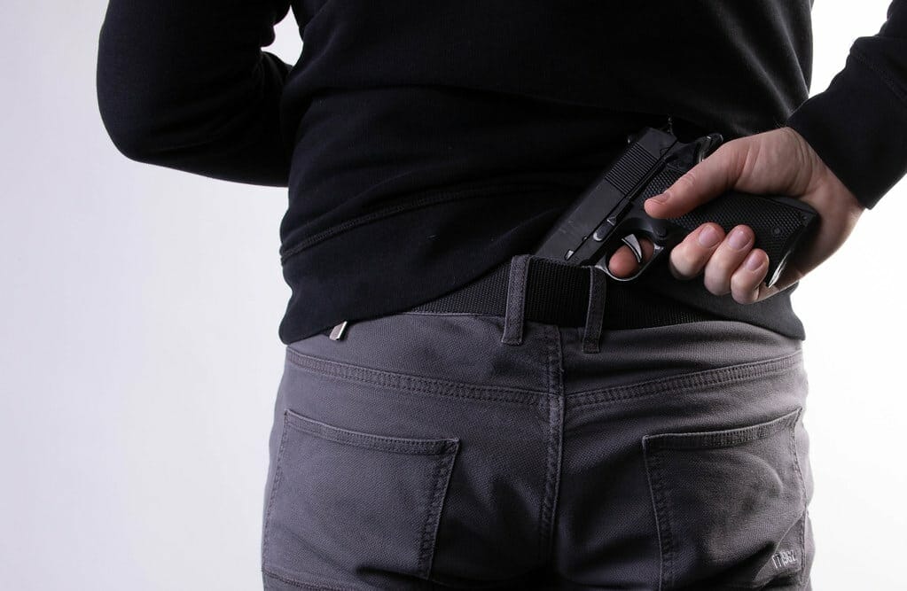 a person holding a gun behind his back