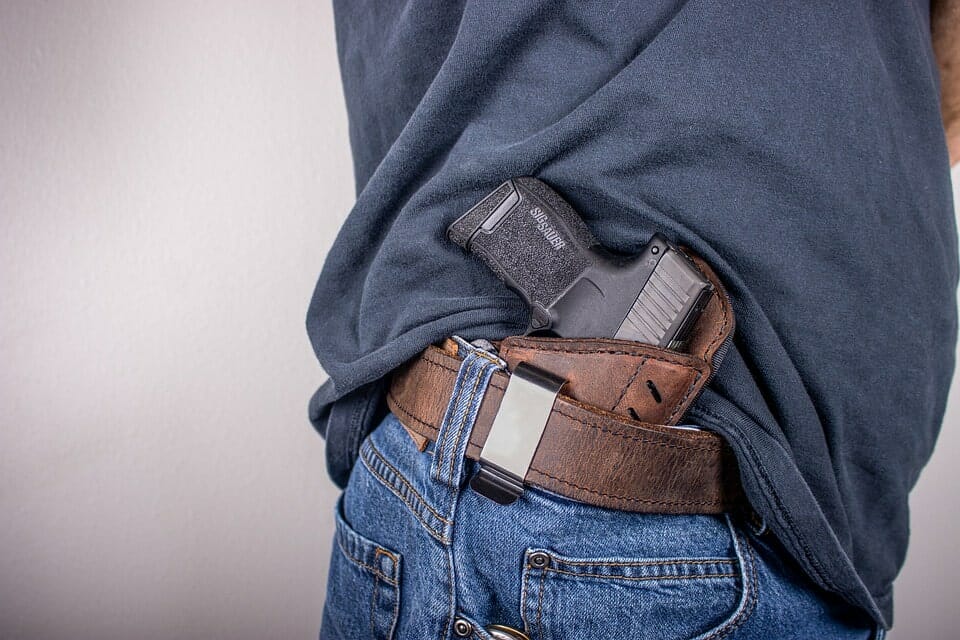 a person carrying a gun on his belt