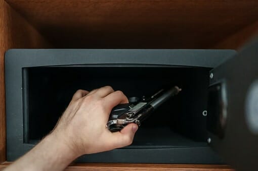 Man putting a gun in a safe