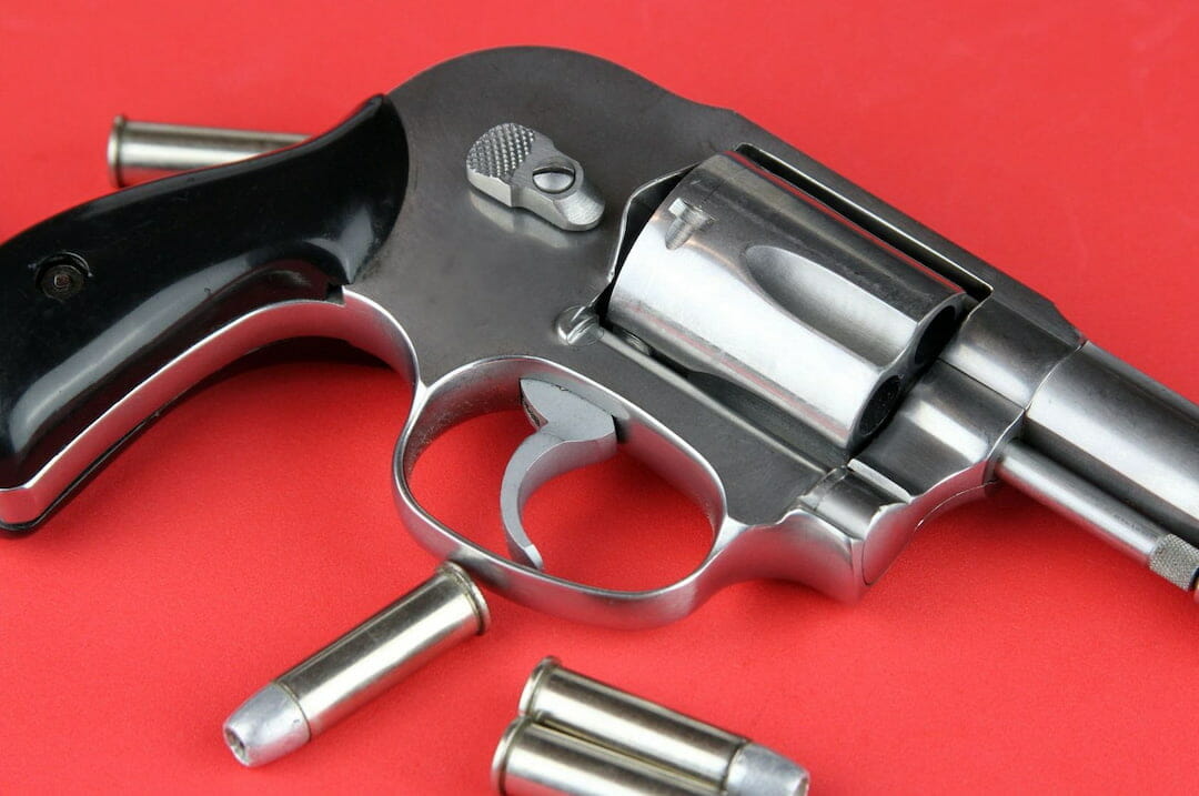 A revolver and the bullets on the red surface